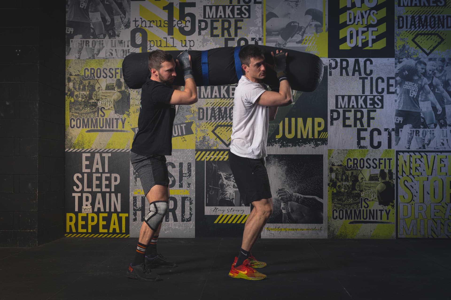Due atleti portano un sandbag insieme durante un allenamento di CrossFit